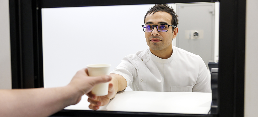 Pharmacist handing cup to patient