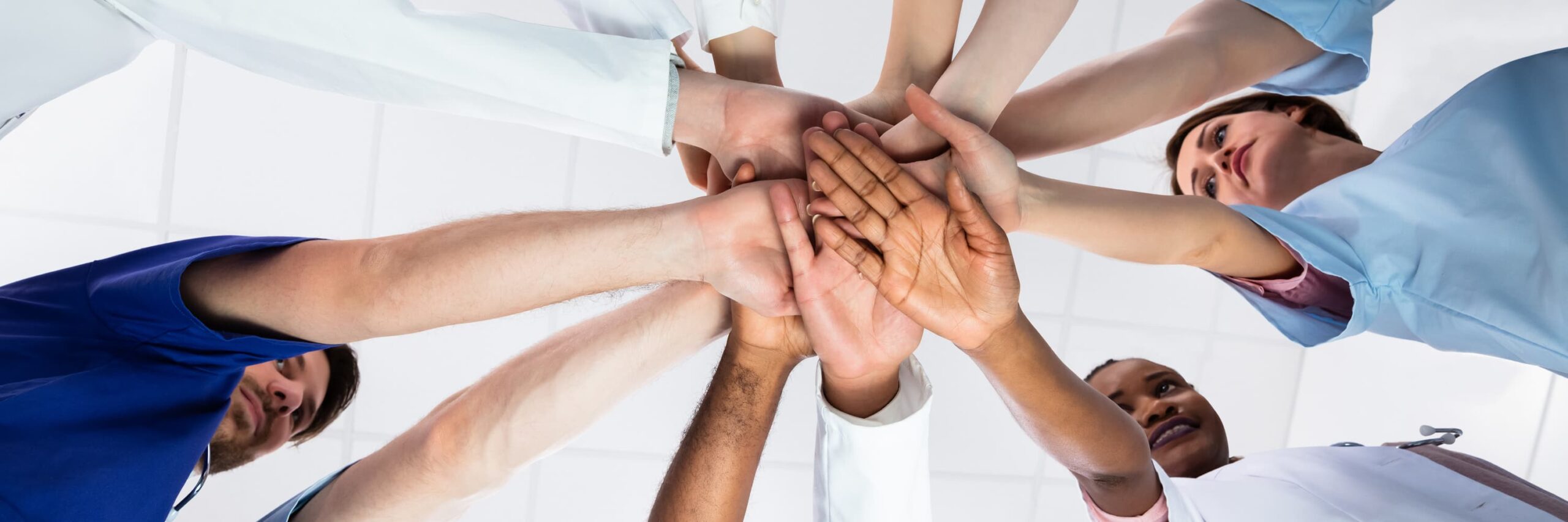 image of a team of medical staff with hands in the middle